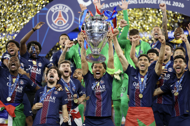 A soccer team holding up a silver cup trophy in celebration.